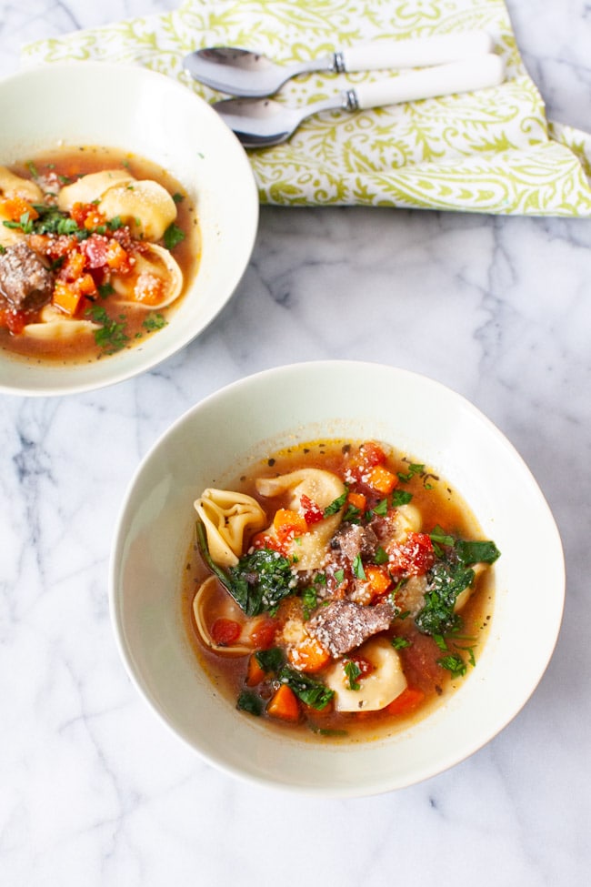 Instant Pot Tortellini Soup from thelittlekitchen.net Two white bowls of Beef Tortellini Soup with two spoons and green napkin in the background.