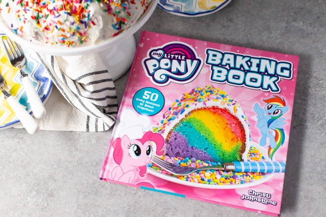 Rainbow Bundt Cake from thelittlekitchen.net My Little Pony Baking Book next to cake plate with rainbow bundt cake