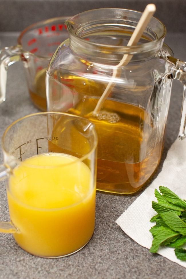 Orange Mint Tea from thelittlekitchen.net orange juice in a cup with tea in a glass jug and fresh mint leaves on a kitchen counter