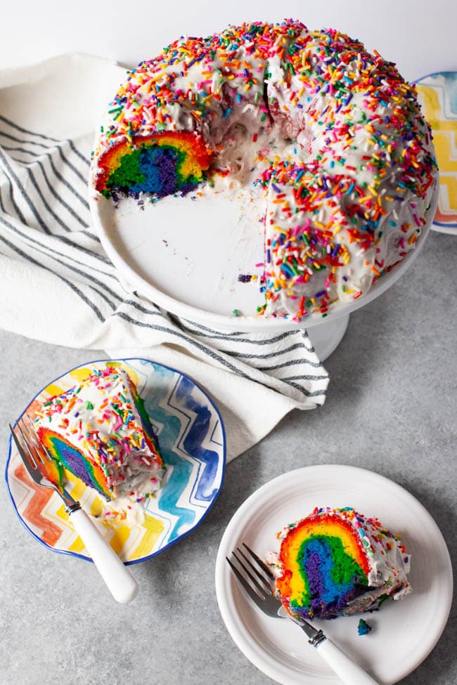 Rainbow Bundt Cake from thelittlekitchen.net Two slices of rainbow cake on two plates with forks next to full tray of cake