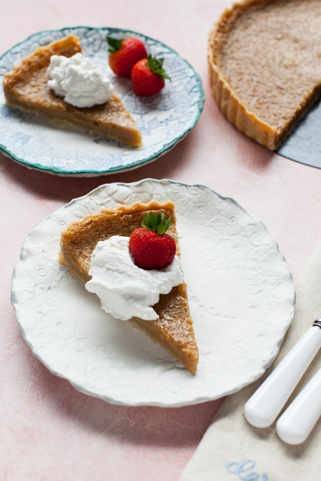 Slice of Sugar Pie on a white plate, topped with whipped cream and strawberry Slice of Sugar Pie on a white plate, topped with whipped cream and strawberry