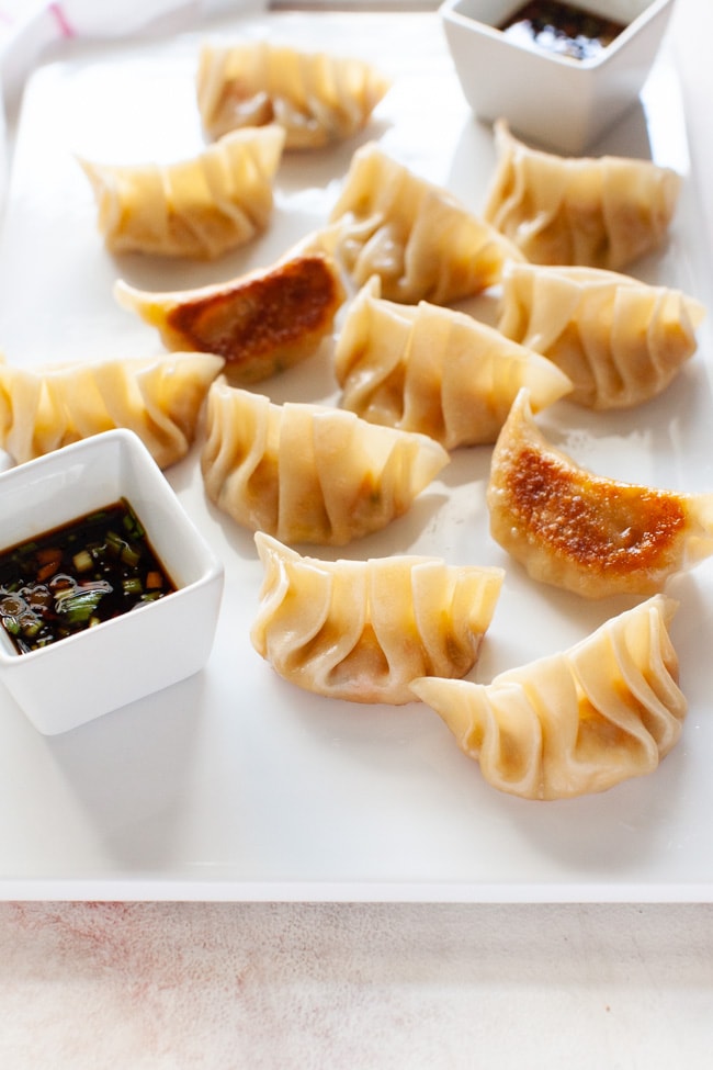 Vegetarian Dumplings from thelittlekitchen.net Vegetarian Dumplings on white serving board with square cups of dipping sauce at opposite corners from thelittlekitchen.net